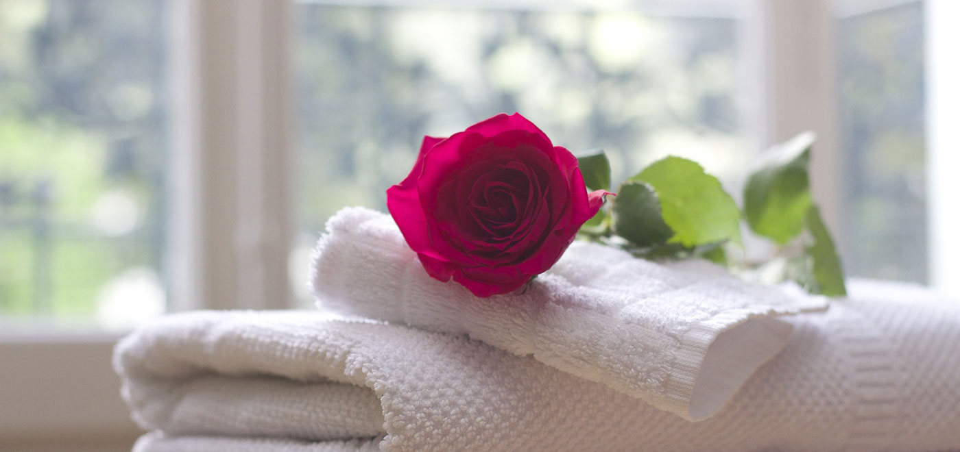 una rosa rossa appoggiata su alcuni asciugamani bianchi e puliti