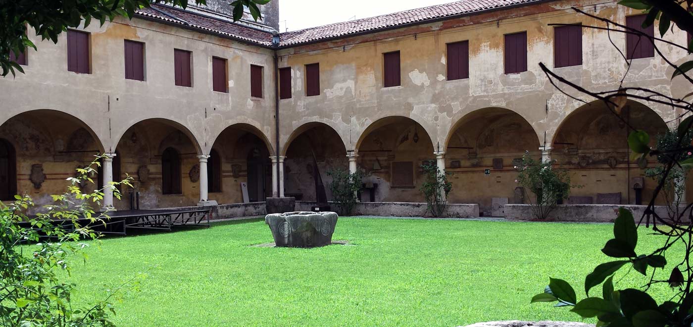 una foto particolare di un chiostro con al centro un grande prato verde